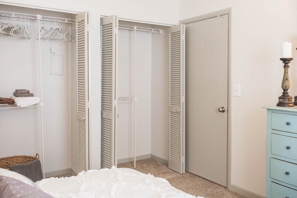 a bedroom with three closets and a bed and a blue dresser