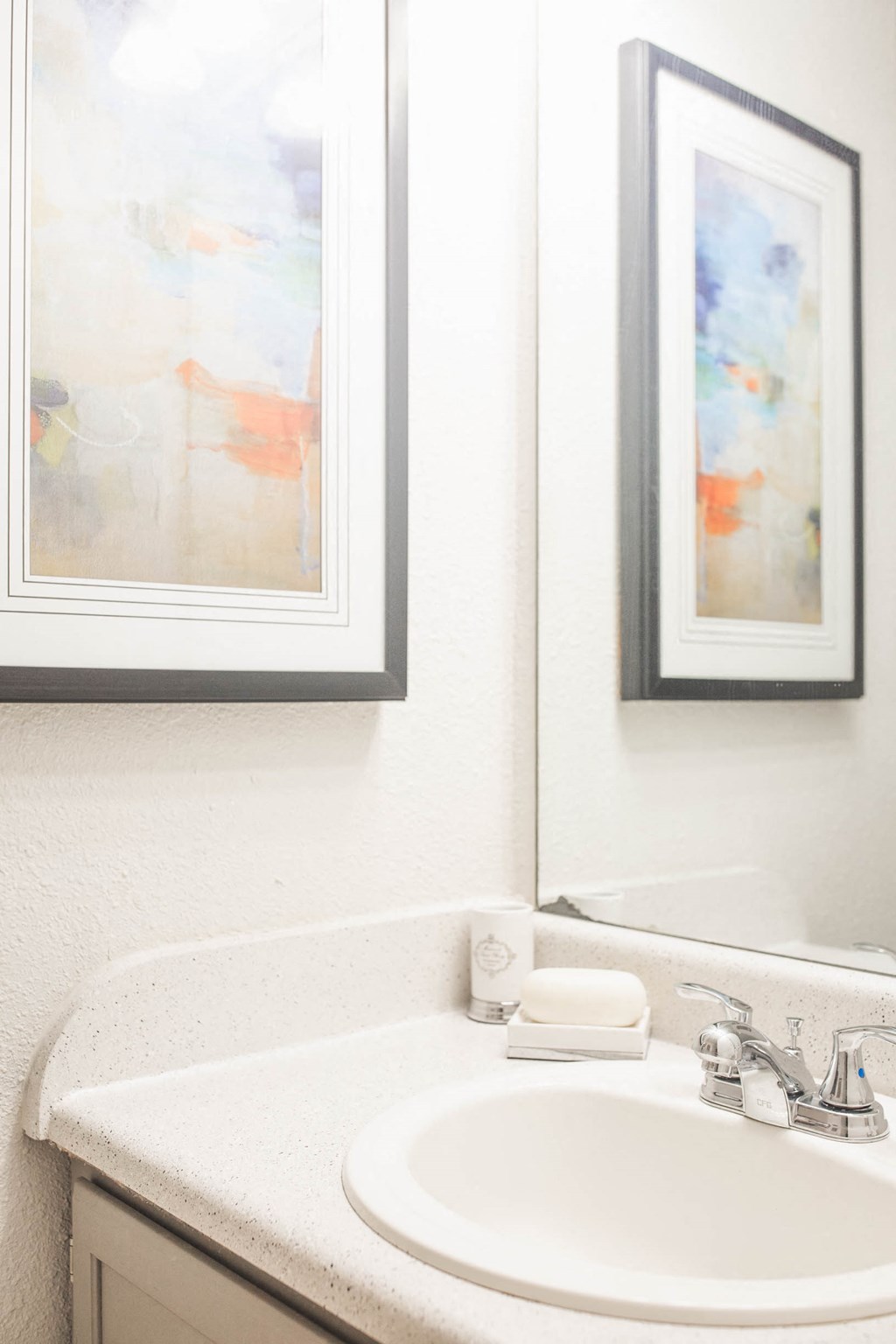 a bathroom with a sink and two paintings on the wall
