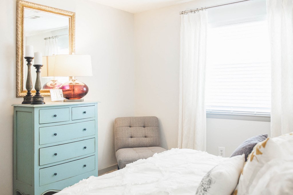 a bedroom with a bed and a chair and a dresser