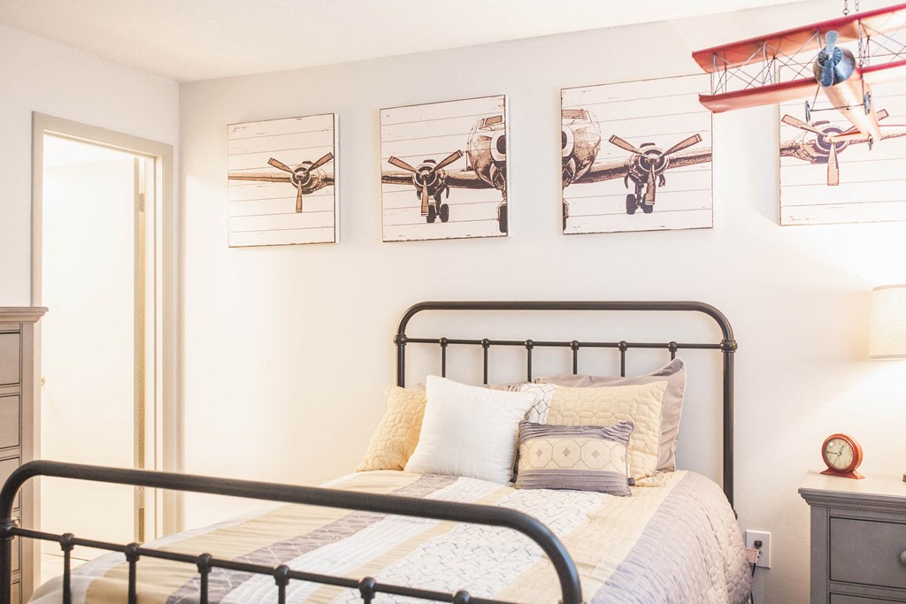 a bedroom with a bed and pictures of planes on the wall