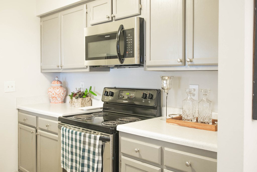 a kitchen with white cabinets and a stove and microwave