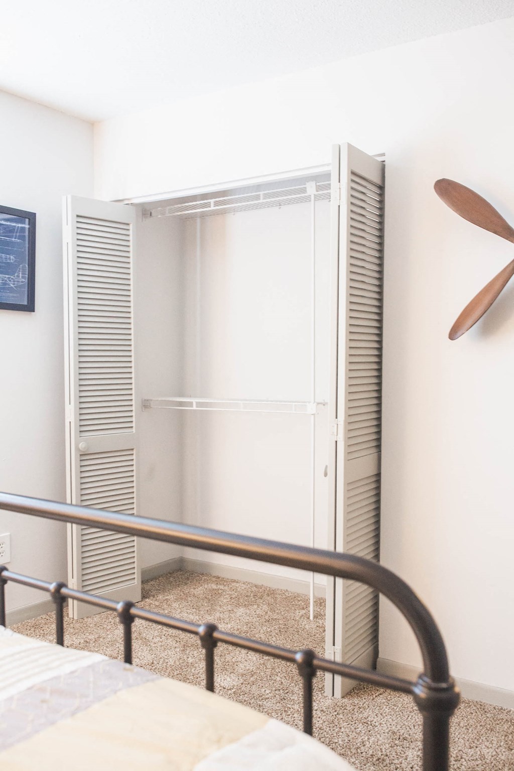 a closet in a bedroom with a bed and a fan