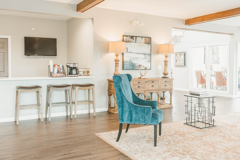 a living room with a blue chair and a bar with stools