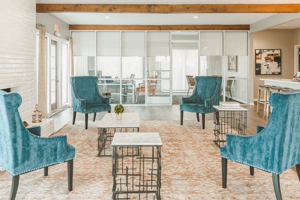 a living room with blue chairs and tables and a large window