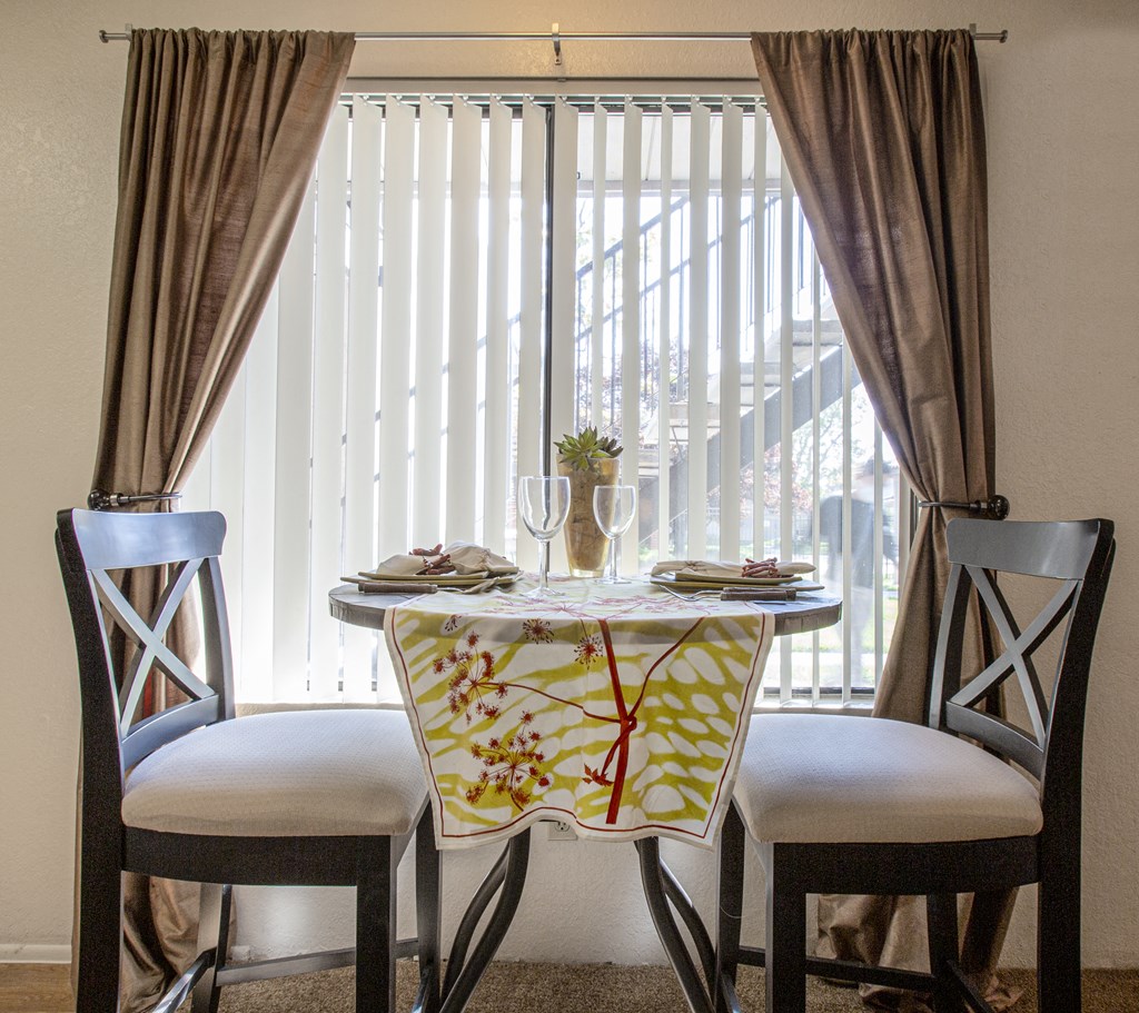 a dining table with two chairs in front of a window