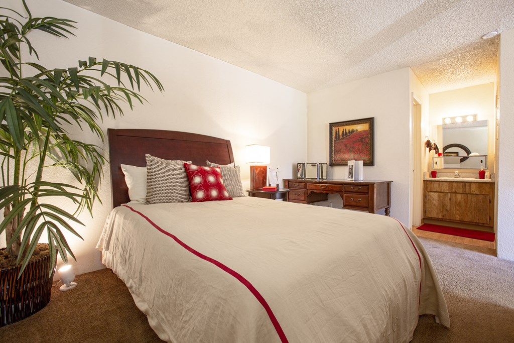 a bedroom with a large bed and a potted plant
