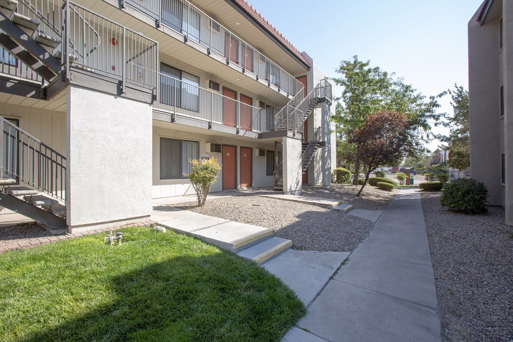 an exterior view of an apartment building with a sidewalk and grass
