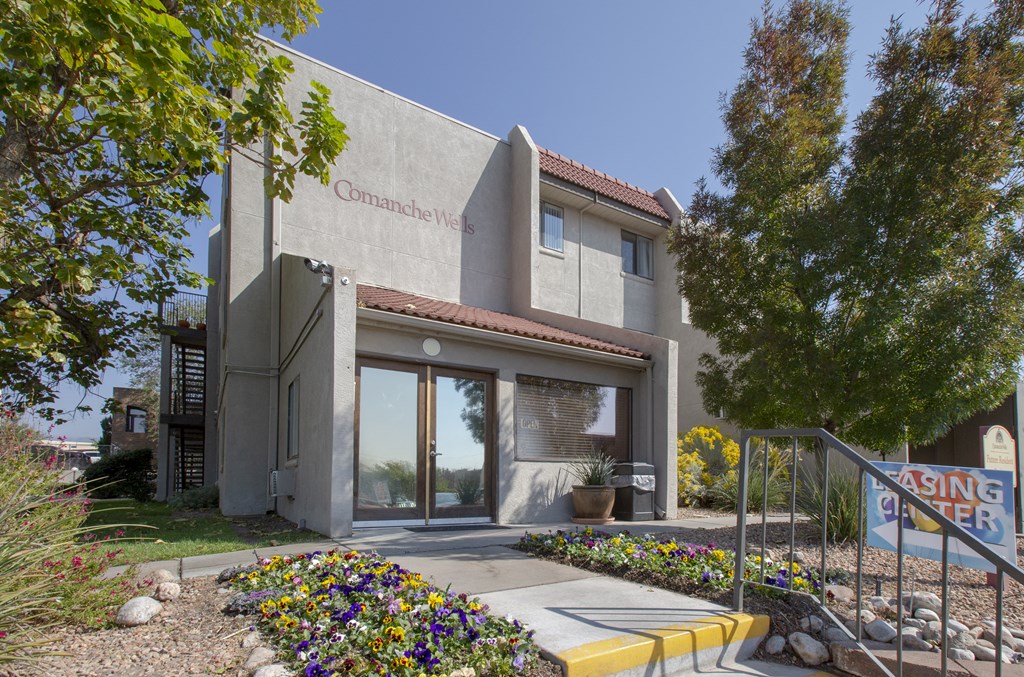 the front of a building with a staircase and flowers in front of it