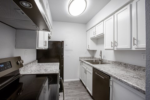 A kitchen with black appliances and white cabinets.