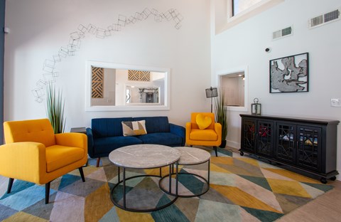 A living room with a yellow chair, blue couch, and a round table.