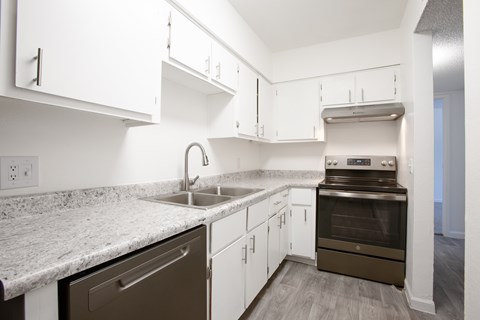 A kitchen with white cabinets and a granite countertop.