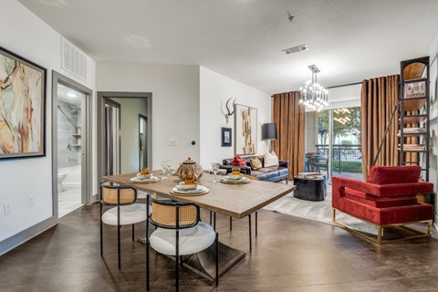 A dining room with a table set for two and a red chair.