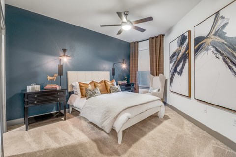 A bedroom with a bed, nightstand, and a ceiling fan.