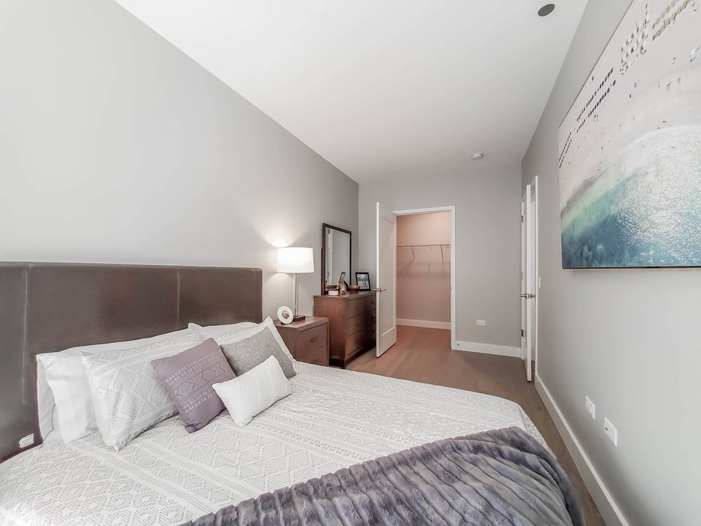 A bedroom with a large bed and a painting on the wall.