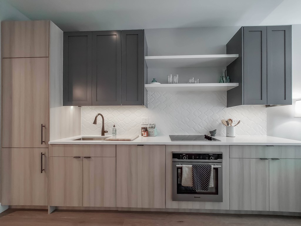 A modern kitchen with a sink, oven, and cabinets.