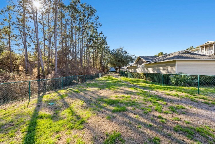 a yard with a chain link fence and a house next to it