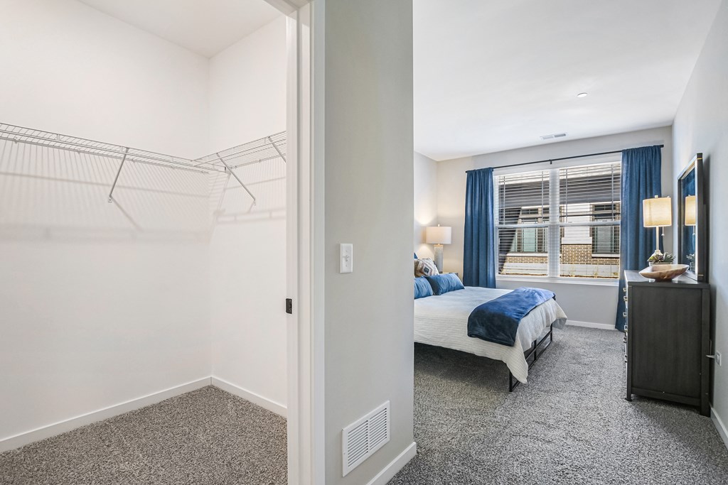 A bedroom with a bed, dresser, and a window with blue curtains.