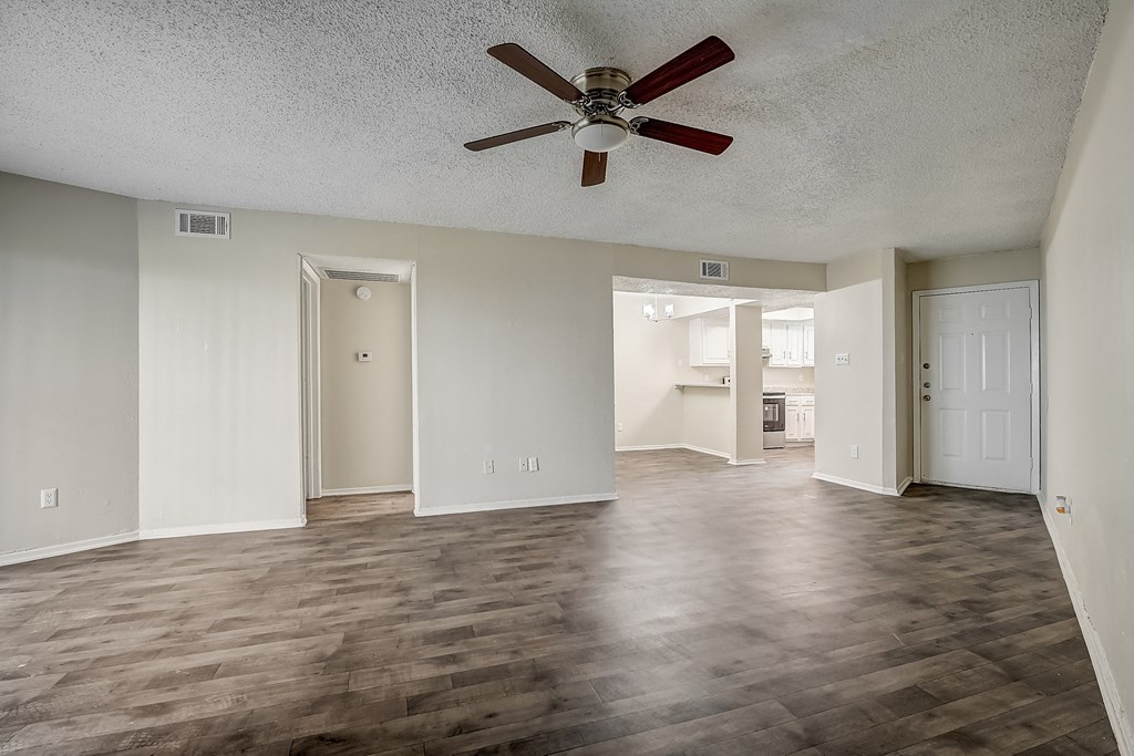 an empty living room with a ceiling fan
