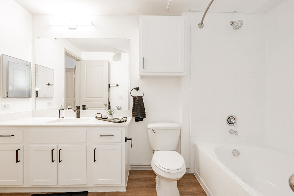 a bathroom with white cabinets and a toilet and a tub