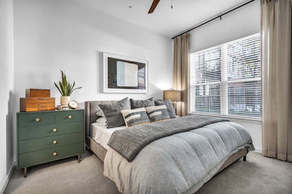a bedroom with a large window and ceiling fan