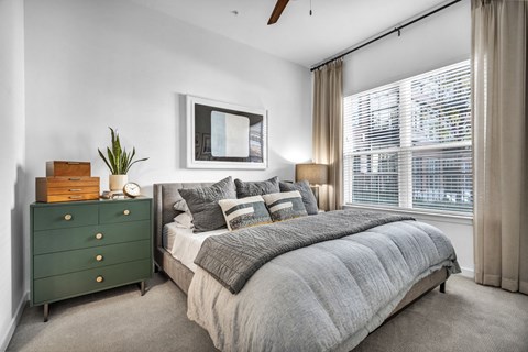 a bedroom with a large window and ceiling fan