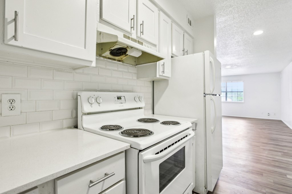 A white kitchen with a stove and refrigerator.
