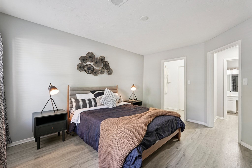 A bedroom with a bed, nightstands, and a wall decoration.