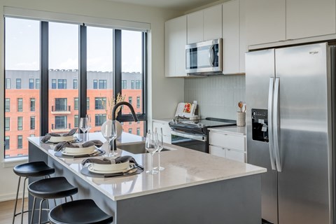 a kitchen with a island and stainless steel appliances and a large window