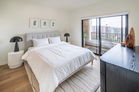 a bedroom with a large bed and a sliding glass door to a balcony