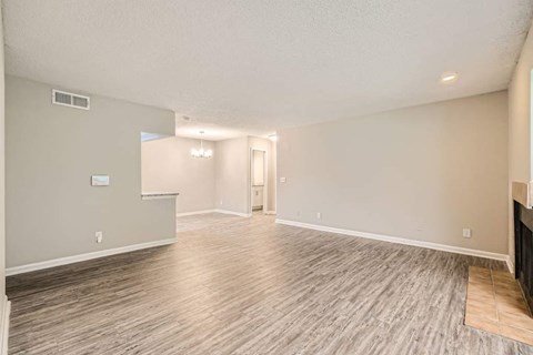 A spacious room with wood flooring and a doorway leading to another room.