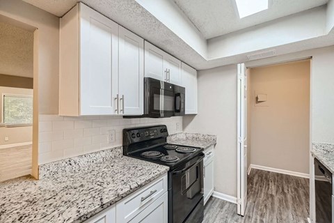 A kitchen with a black stove top oven and white cabinets.