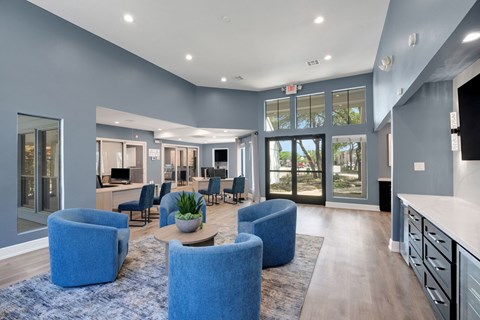 A spacious living room with blue chairs and a wooden floor.