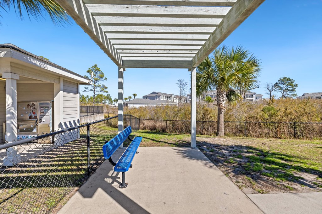 A blue bench sits under a white canopy in a sunny park.
