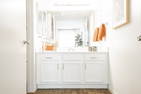 a bathroom with white cabinets and a sink and a mirror