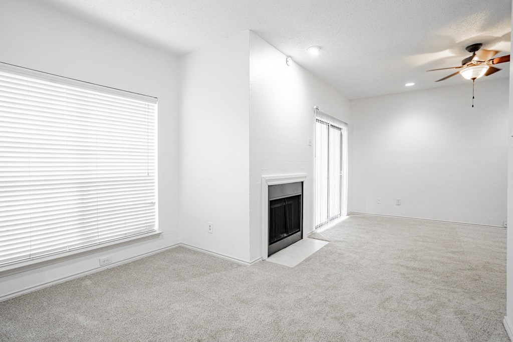 an empty living room with a fireplace and a ceiling fan