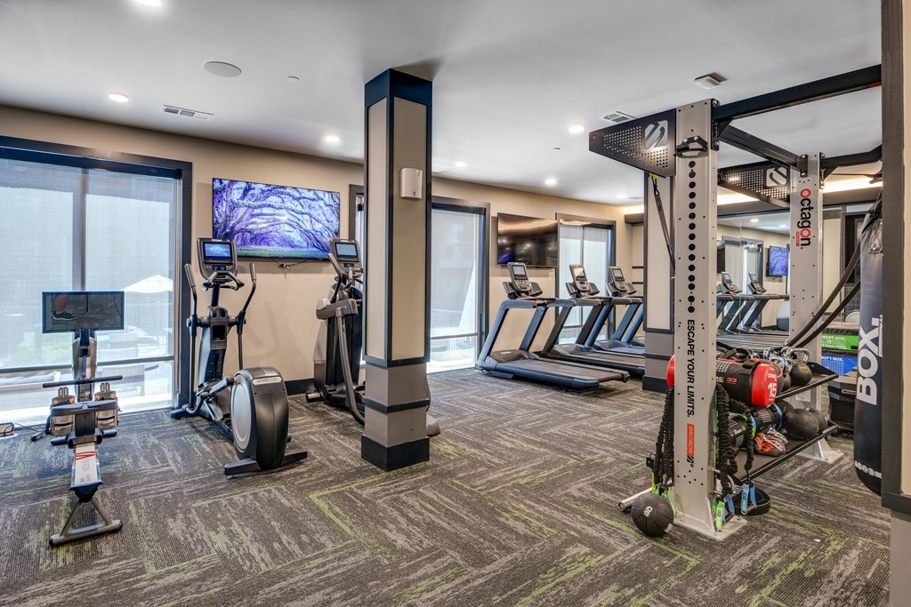 A gym with a variety of equipment including treadmills, weights, and a television.