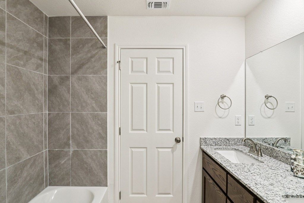 A bathroom with a white door, a white sink, and a white tub.