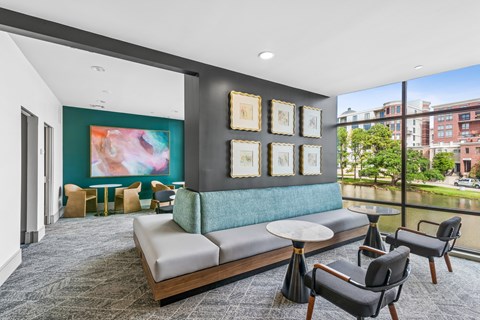 A living room with a grey sofa, a round table and a painting on the wall.