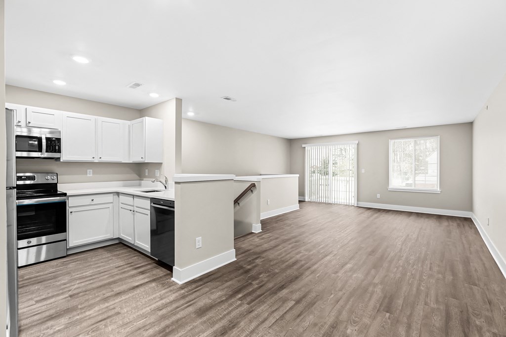 the living room and kitchen of a new home with white walls and wood flooring