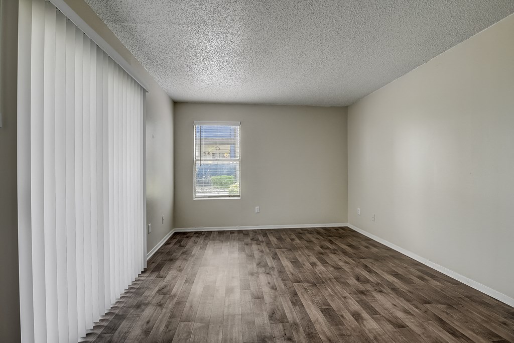 an empty living room with a window and curtains