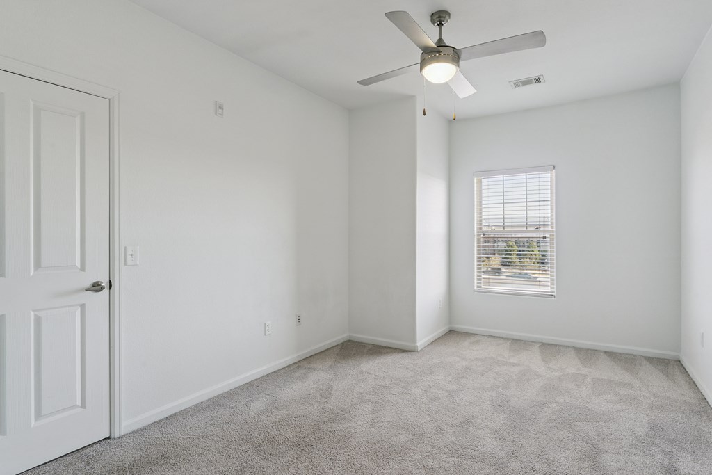A room with a ceiling fan and a window with blinds.