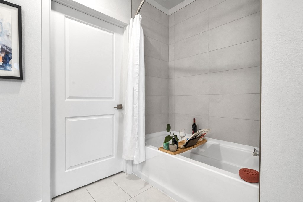 a white bathroom with a tub and a white door