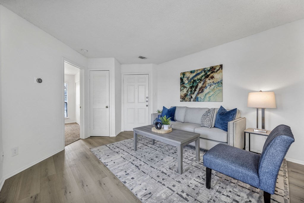 A living room with a grey sofa, a grey armchair, a grey coffee table, and a grey rug.