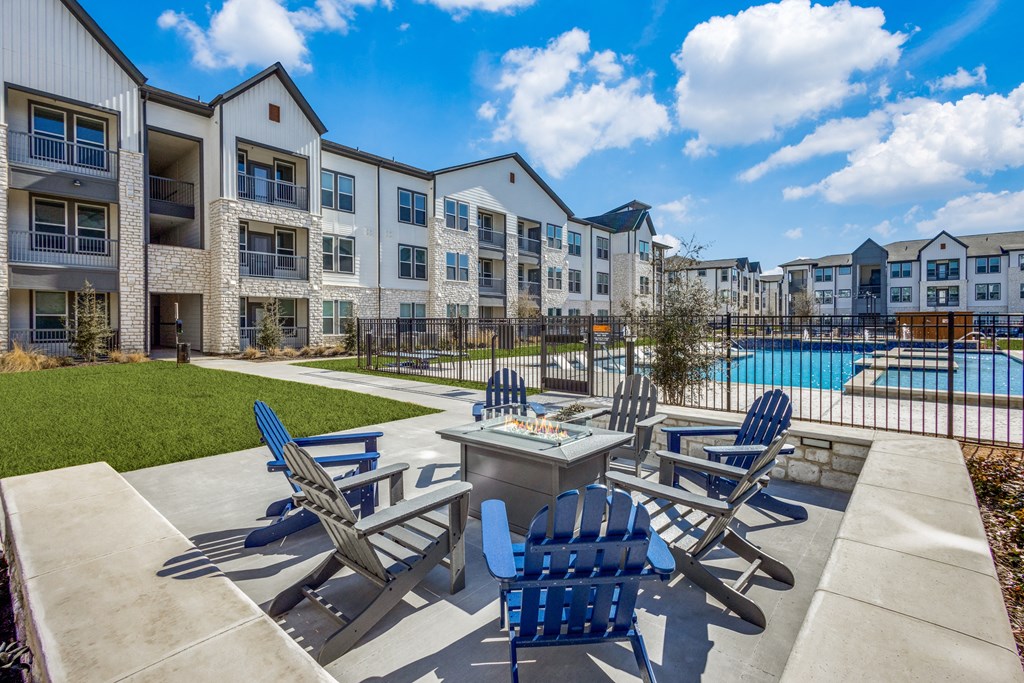 an outdoor patio with chairs and a fire pit and an apartment building