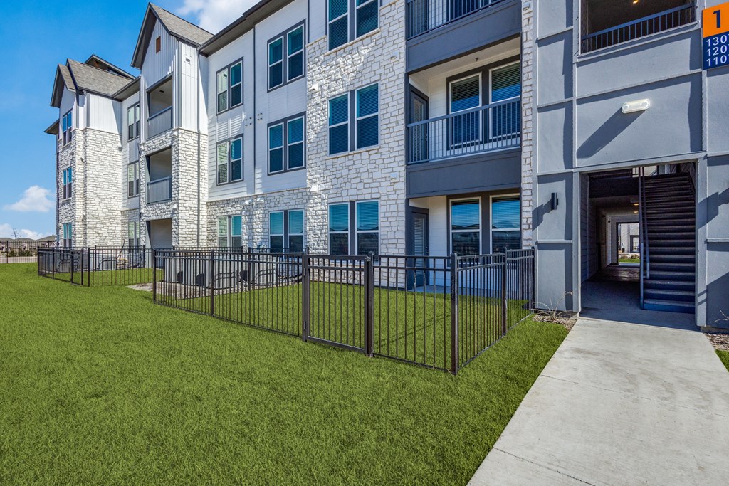 an exterior view of an apartment building with green grass and a sidewalk