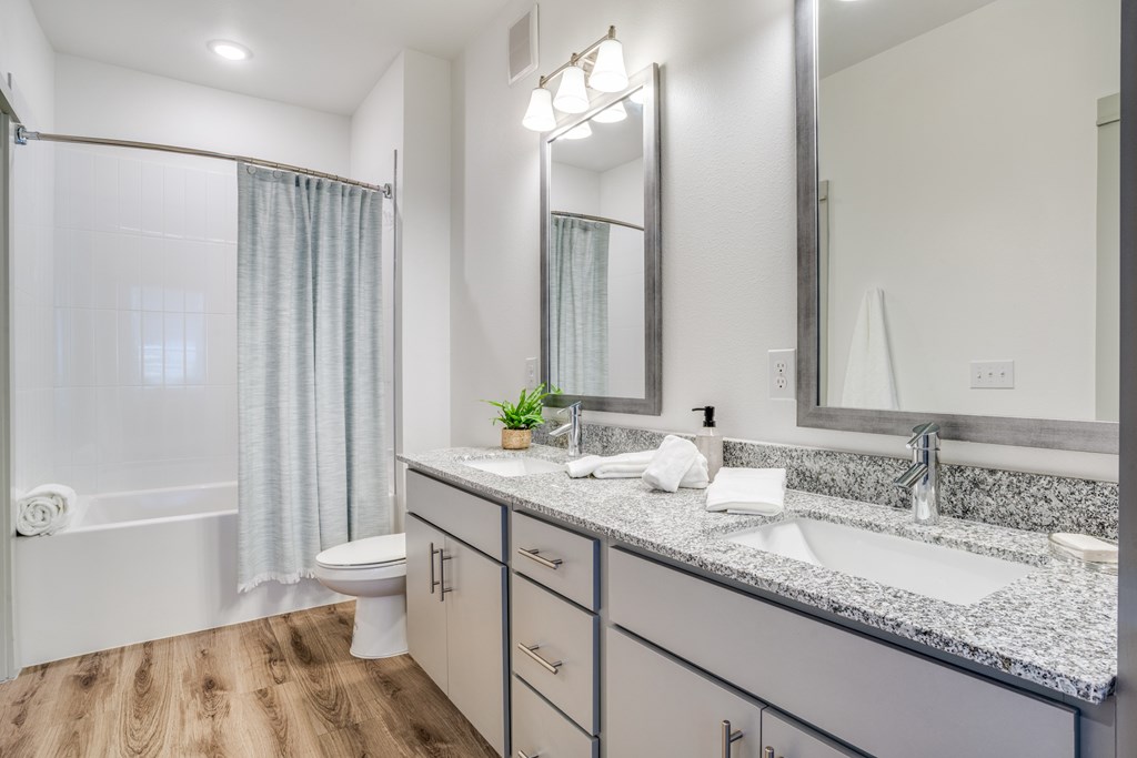 A bathroom with a white tub, sink, and mirror.