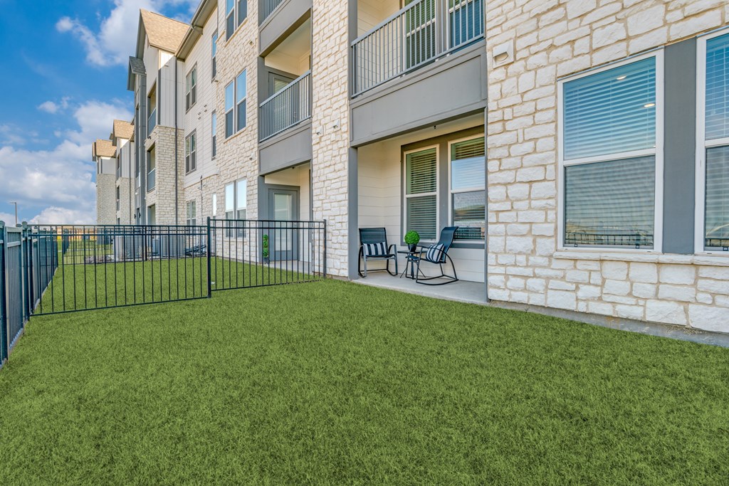 A grassy area in front of a building with a black fence.