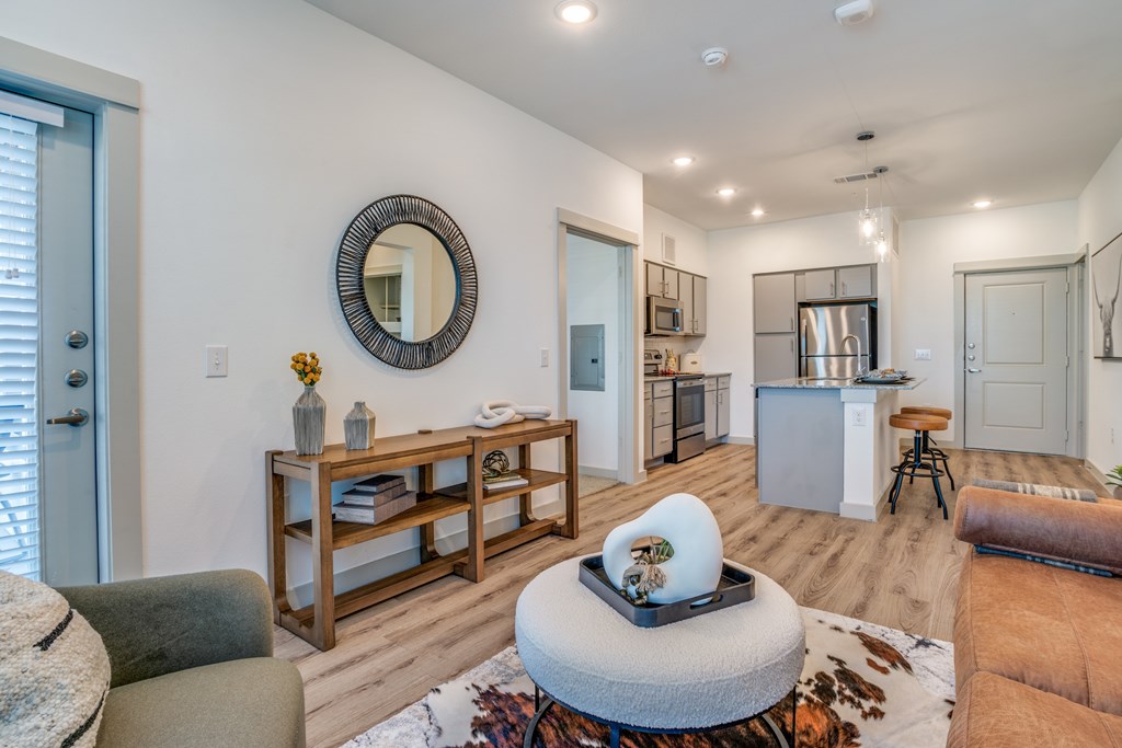 A modern living room with a round mirror and a white coffee table.