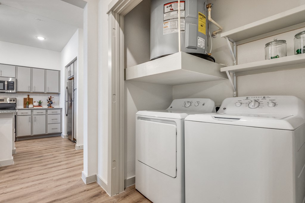 a washer and dryer in a laundry room with a kitchen in the background