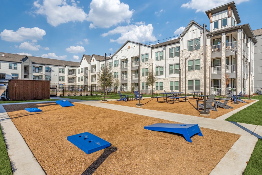 an outdoor playground with benches and picnic tables in front of an apartment building